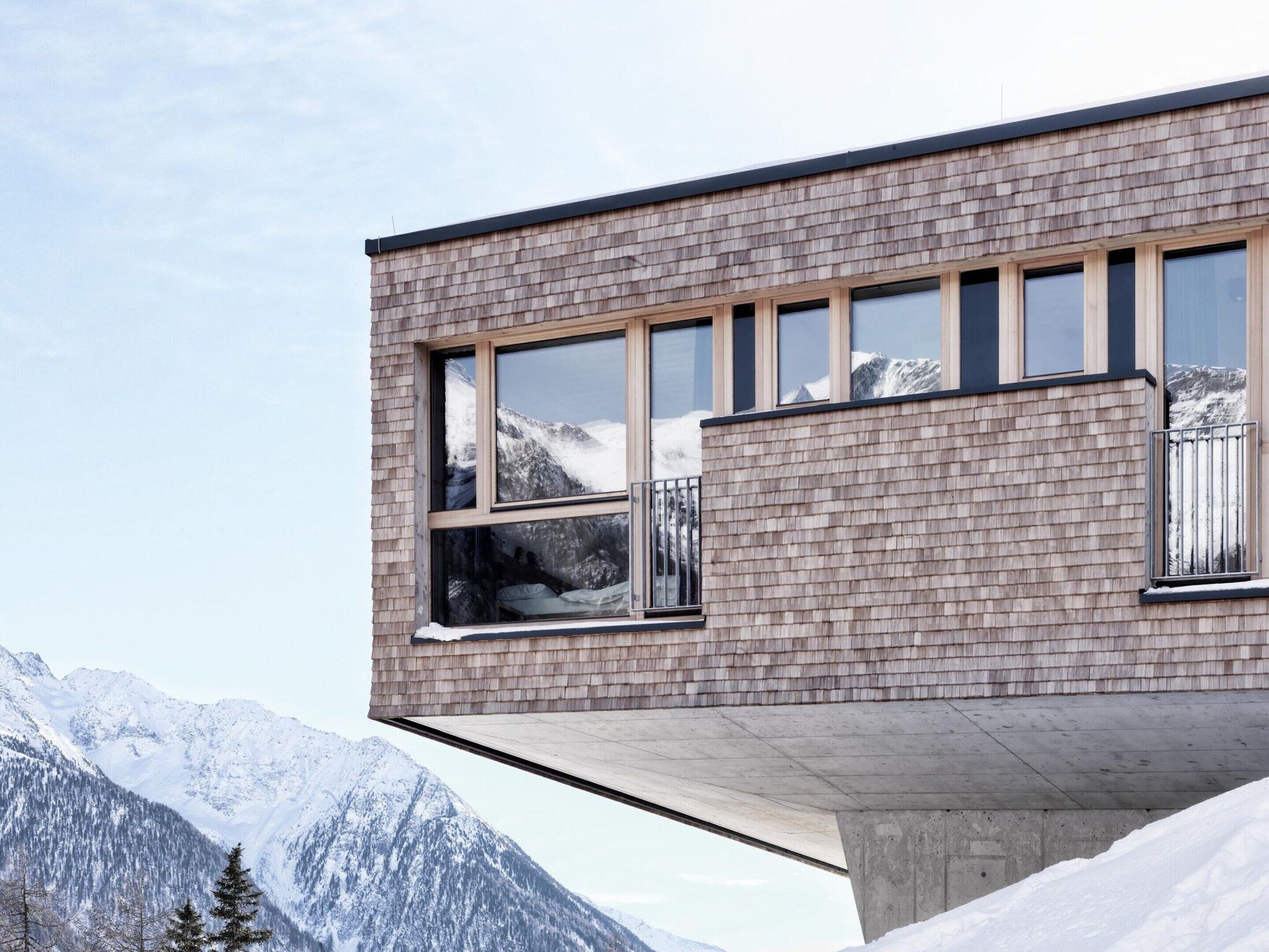 A modern building with large windows and a view of snow-covered mountains.