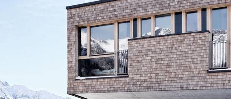 A modern building with large windows and a view of snow-covered mountains.