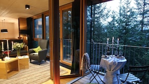 A modern living room with a sofa, a coffee table, and a dining area with a table set for two. - Chalet Resort in Kals am Grossglockner (Kals am Grossglockner)