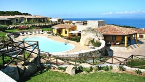 A resort with a swimming pool, outdoor seating, and a view of the sea.