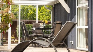 An outdoor patio with wicker furniture, a table, and chairs. - Ferienhaus Seebrise mit Sauna am Dummer See (Dümmer)