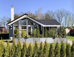 Ett modernt hus med ett sluttande tak, stora fönster och en skorsten.