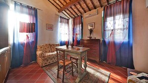 A cozy room with a wooden ceiling, a dining table, a sofa, and a patterned rug.