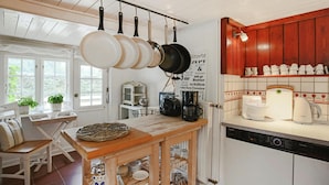 A kitchen with hanging pots, a coffee maker, and a dishwasher. - Reetgedecktes Ferienhaus in Humptrup (Humptrup)