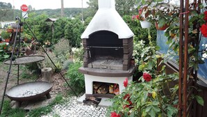A traditional stone oven with a chimney, surrounded by a garden with various plants and flowers. - Holiday House in Wapnica Near Emerald Lake (Międzyzdroje)