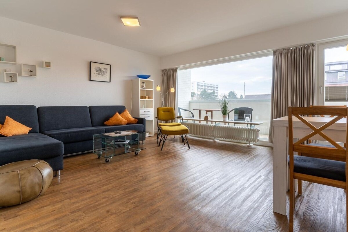 Una sala de estar moderna con un sofá, un sillón y un comedor con una mesa y sillas.