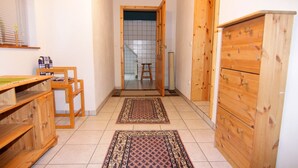 Un couloir étroit, avec des meubles en bois, un sol carrelé et un tapis à motifs.