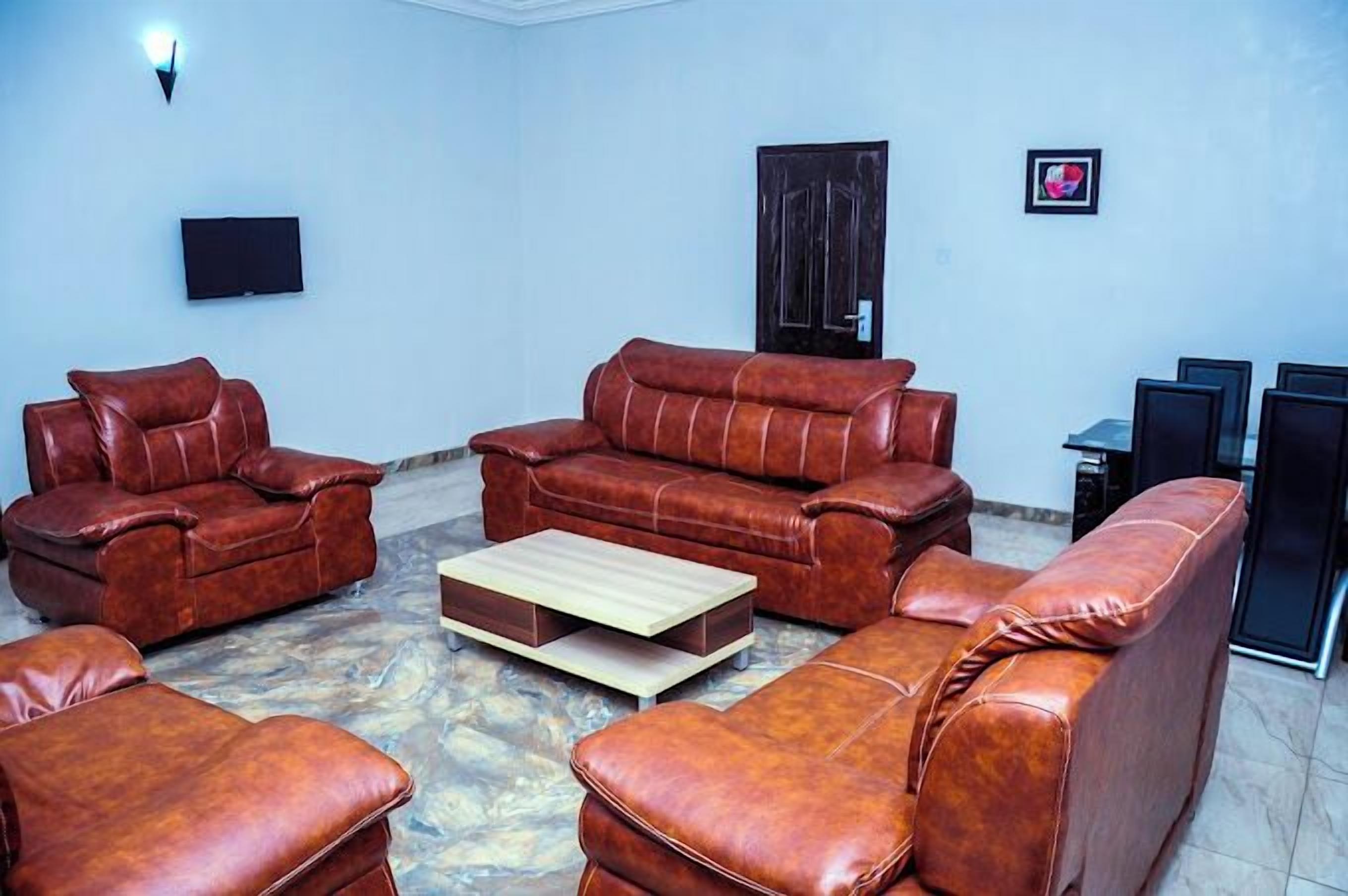 A living room with a brown leather sofa set, a coffee table, and a flat-screen TV mounted on the wall.