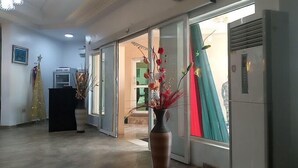 A hotel lobby with a reception desk, a vase with flowers, and a sliding glass door leading to a balcony. - Rolak Hotel and Suites (Ijebu Ode)