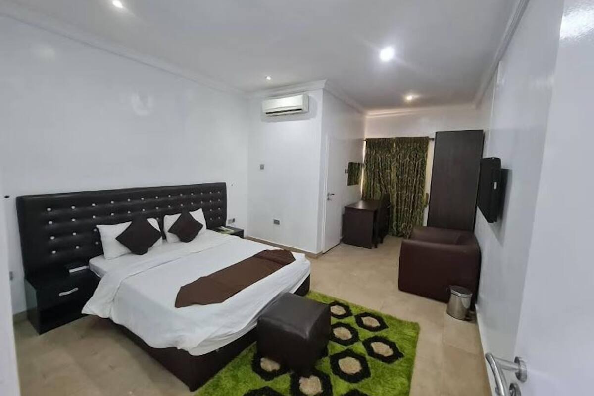 Une chambre moderne avec un grand lit, un petit coin salon et une salle de bain.