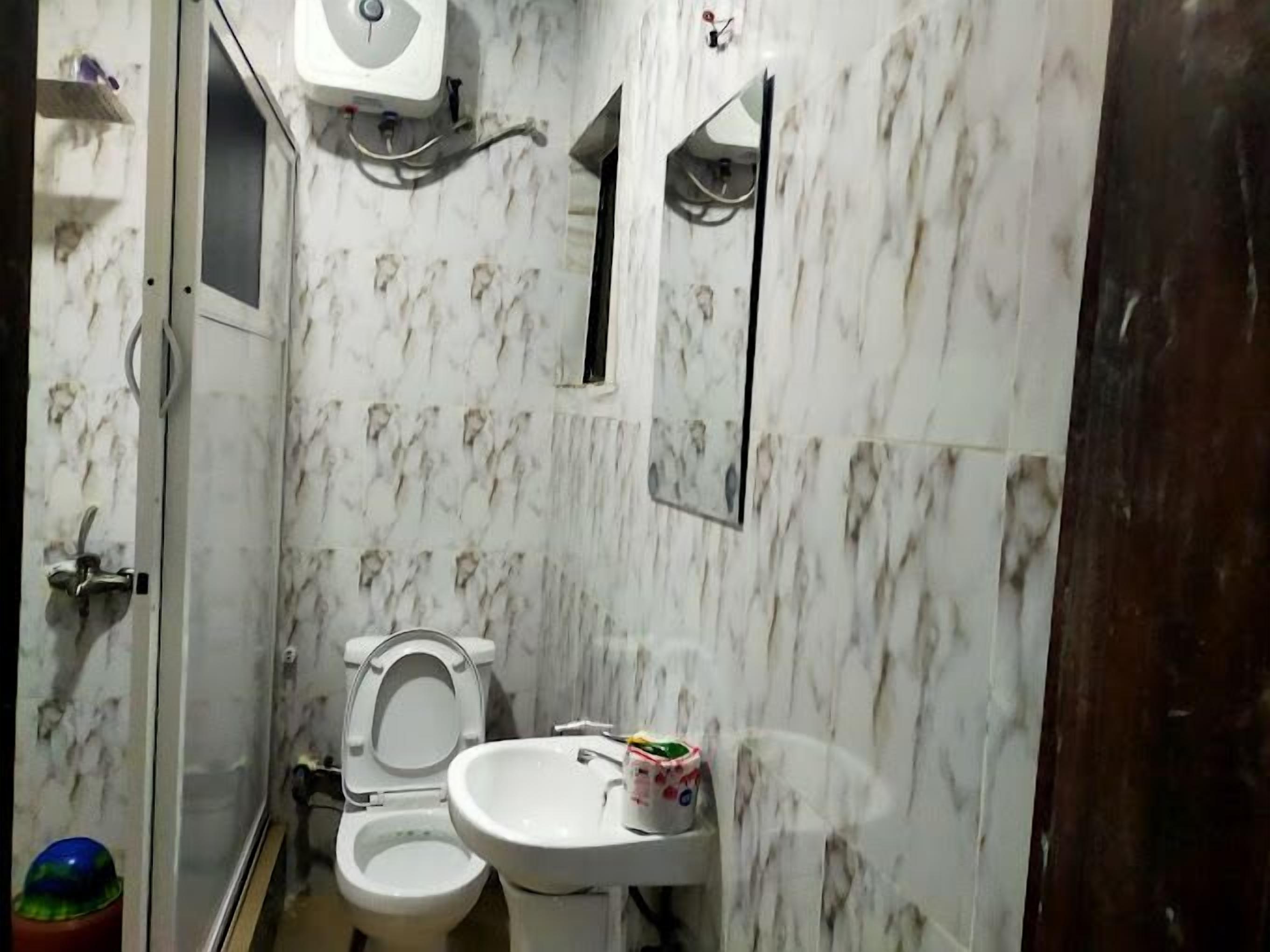 A bathroom with a toilet, sink, and mirror.