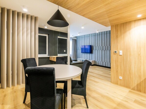 A modern conference room with a round table, black chairs, and a large black pendant light. - Luxury 3-room Apartment by the Beach (Ustka)