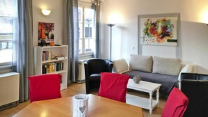 Un soggiorno moderno con un divano, poltrone, un tavolino da caffè, una libreria e un quadro appeso al muro.