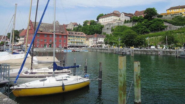 Una marina con imbarcazioni ormeggiate, una passeggiata sul lungomare e edifici dall'architettura tradizionale.