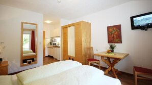 A hotel room with a bed, a wooden desk, a chair, a television, and a painting on the wall.