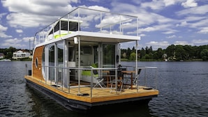 Une péniche dotée d’une terrasse, d’un coin repas et d’un espace de vie comprenant un téléviseur et des sièges.
