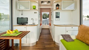Un intérieur compact comprenant un coin cuisine, un espace repas et un coin salon avec vue sur l’eau.