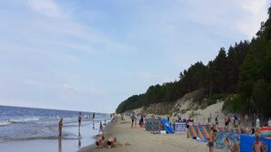 A beach with people, umbrellas, and beach chairs. - Chalet by Baltic Sea Near Wiselka Lake (Międzyzdroje)