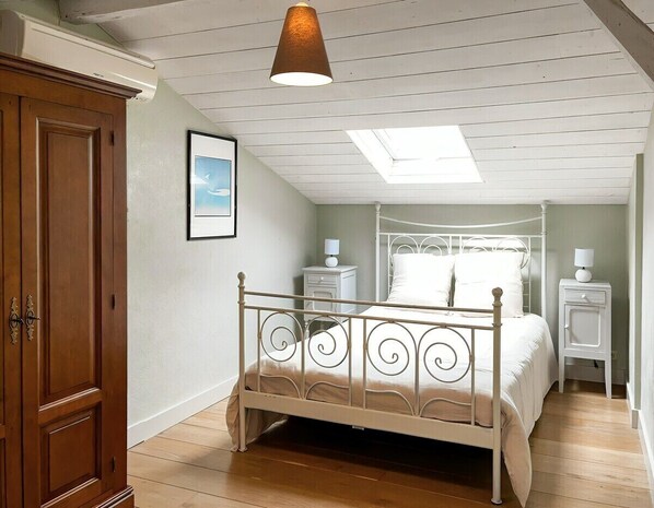 A bedroom with a four-poster bed, a wooden wardrobe, a skylight, and a white nightstand with a lamp. - 3-star country house, swimming pool (Fiac)