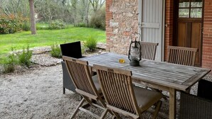 An outdoor wooden table with chairs, a lantern, and a laptop on a gravel path. - 3-star country house, swimming pool (Fiac)