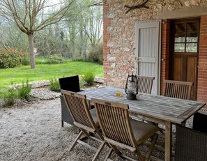 An outdoor wooden table with chairs, a lantern, and a laptop on a gravel path. - 3-star country house, swimming pool (Fiac)