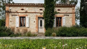 A rustic stone building with a wooden door and shuttered windows, surrounded by a grassy field with daisies. - 3-star country house, swimming pool (Fiac)