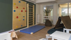 A playroom with a climbing wall, a soft play mat, a table, chairs, and a bean bag. - Komfortable Wohnung mit SPA und Pool (Langeoog)