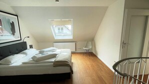 A bedroom with a bed, a radiator, a window, and a door. - Komfortable Wohnung mit SPA und Pool (Langeoog)