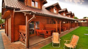 Un lodge in legno con patio coperto, posti a sedere all'aperto e un prato curato.
