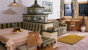 A cozy living room with a dining table, striped sofa, and a kitchen area with a stove. - Flat in St. Anton am Arlberg With Balcony (Sankt Anton am Arlberg)