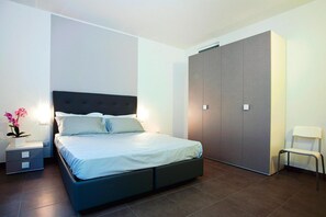 Une chambre moderne avec un grand lit, une table de chevet, une armoire et une chaise.