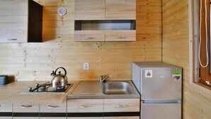 Une cuisine de taille réduite, dotée de meubles en bois, d’une cuisinière à gaz, d’un évier et d’un réfrigérateur.