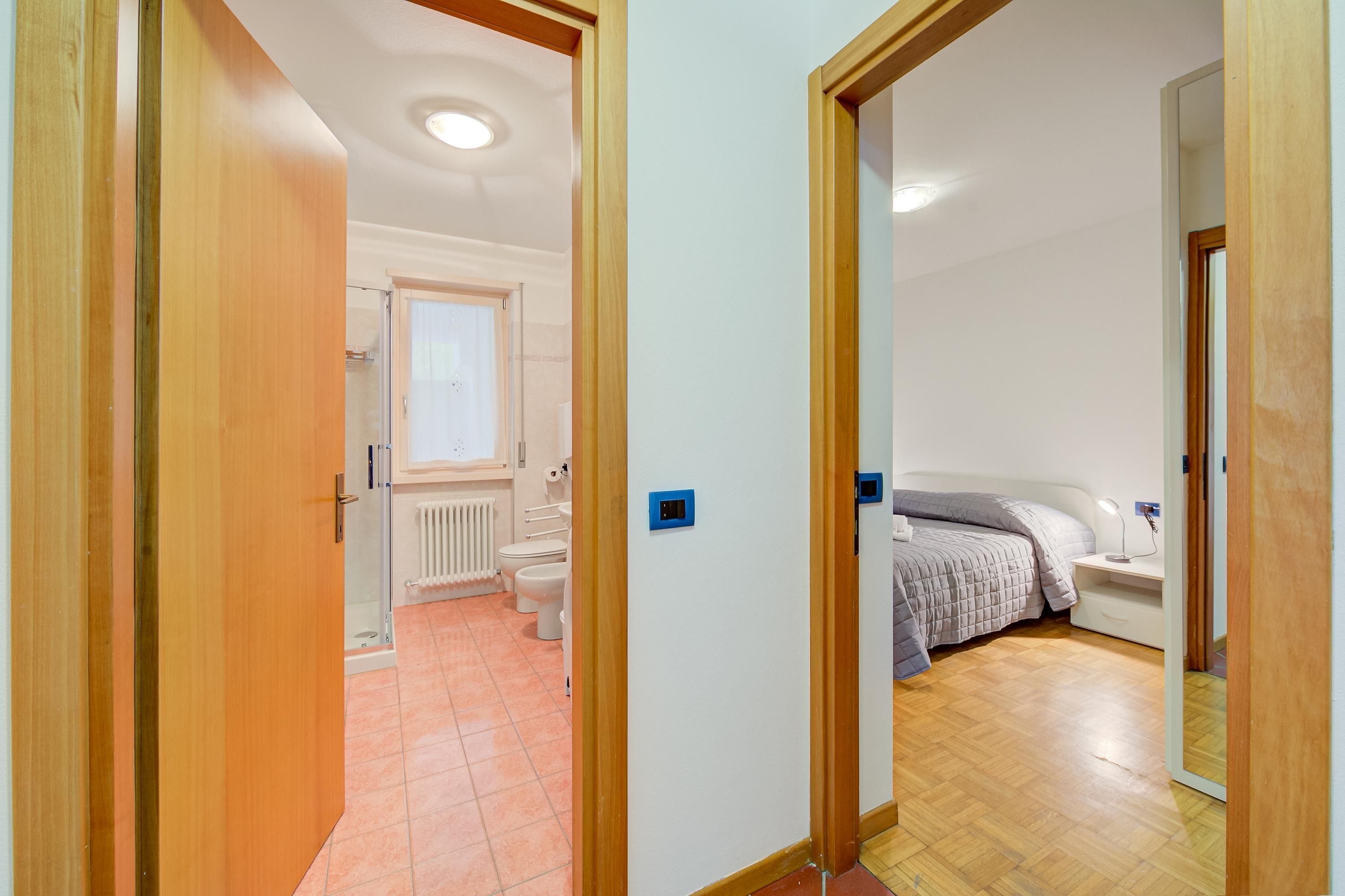 A bedroom with a bed, bedside table, and a mirror.