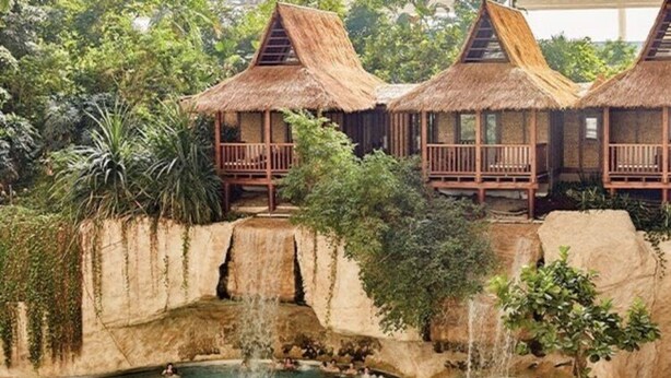 A resort with thatched-roof bungalows, a central pool with waterfalls, and lush greenery. - Apartment SL Lounge, Luebben (Lübben (Spreewald))