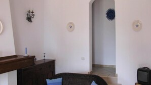 A living room with a sofa, a television on a stand, a wooden cabinet, and a staircase leading to another room. - Apartment on Costa Rei With Sea View (Muravera)