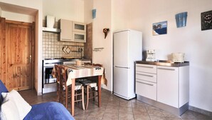 A compact kitchen with a dining table, a refrigerator, and a coffee maker. - Apartment on Costa Rei With Sea View (Muravera)