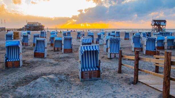 A beach with rows of striped beach chairs and a wooden walkway. - Ferienwohnung in St. Peter-ording (St. Peter-Ording)
