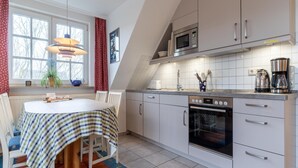 A modern kitchen with white cabinets, a built-in oven, and a microwave. - Ferienwohnung in St. Peter-ording (St. Peter-Ording)