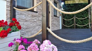 A building entrance with a stone facade, wooden deck, and rope barrier. - Holiday Home Miedzywodzie Near Sandy Beach (Dziwnów)