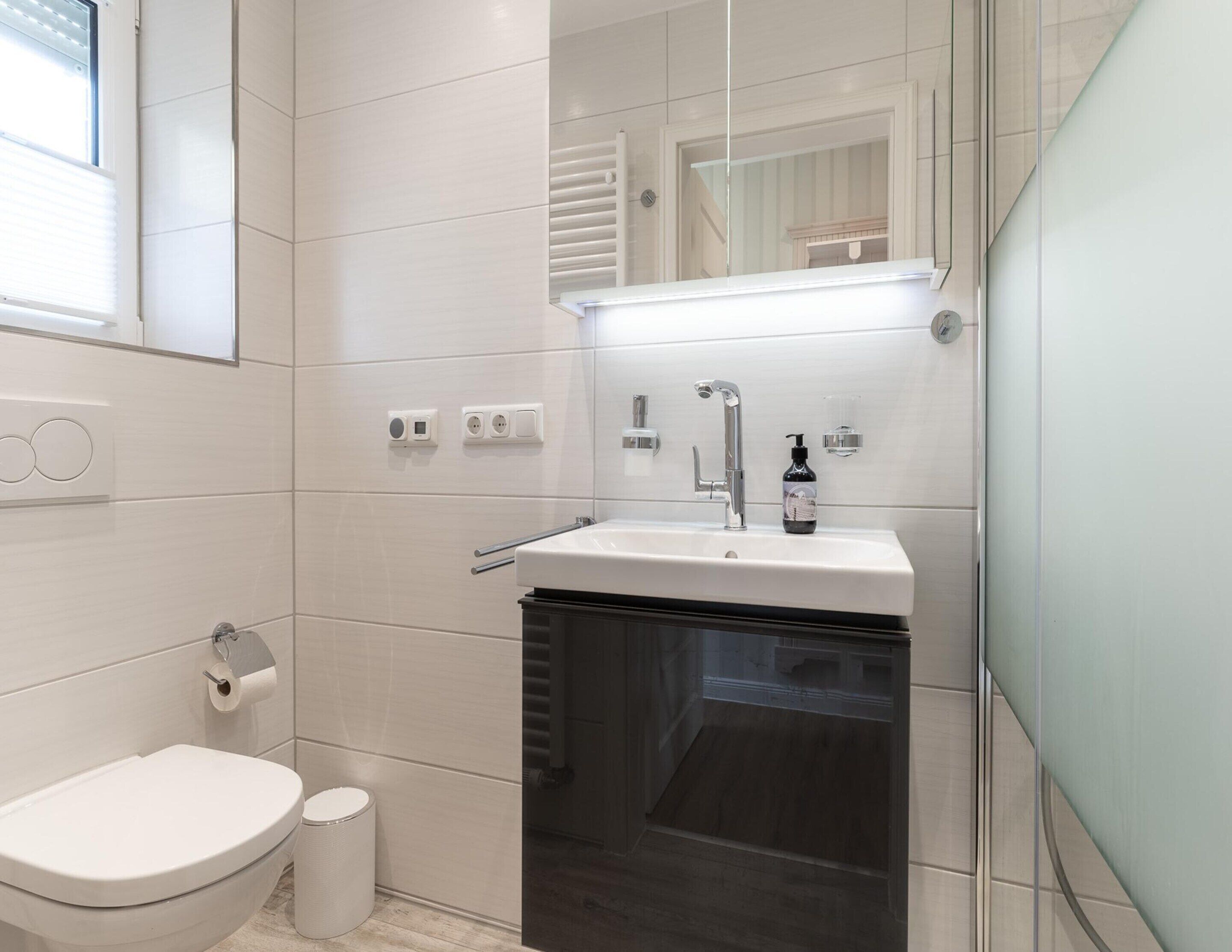 Un baño moderno con inodoro, lavabo y espejo.