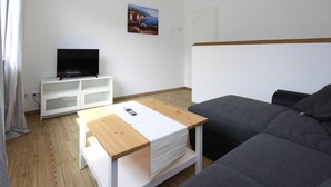 En moderne stue med et træsofabord, en grå sofa, et hvidt tv-skab og et billede på væggen.