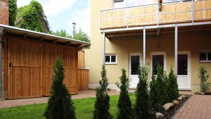 En toetagers bygning med en træbalkon, en garage og en velholdt have med buske samt en belagt sti.
