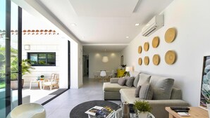 A modern living room with a sofa, coffee table, and a dining area with chairs and a table.