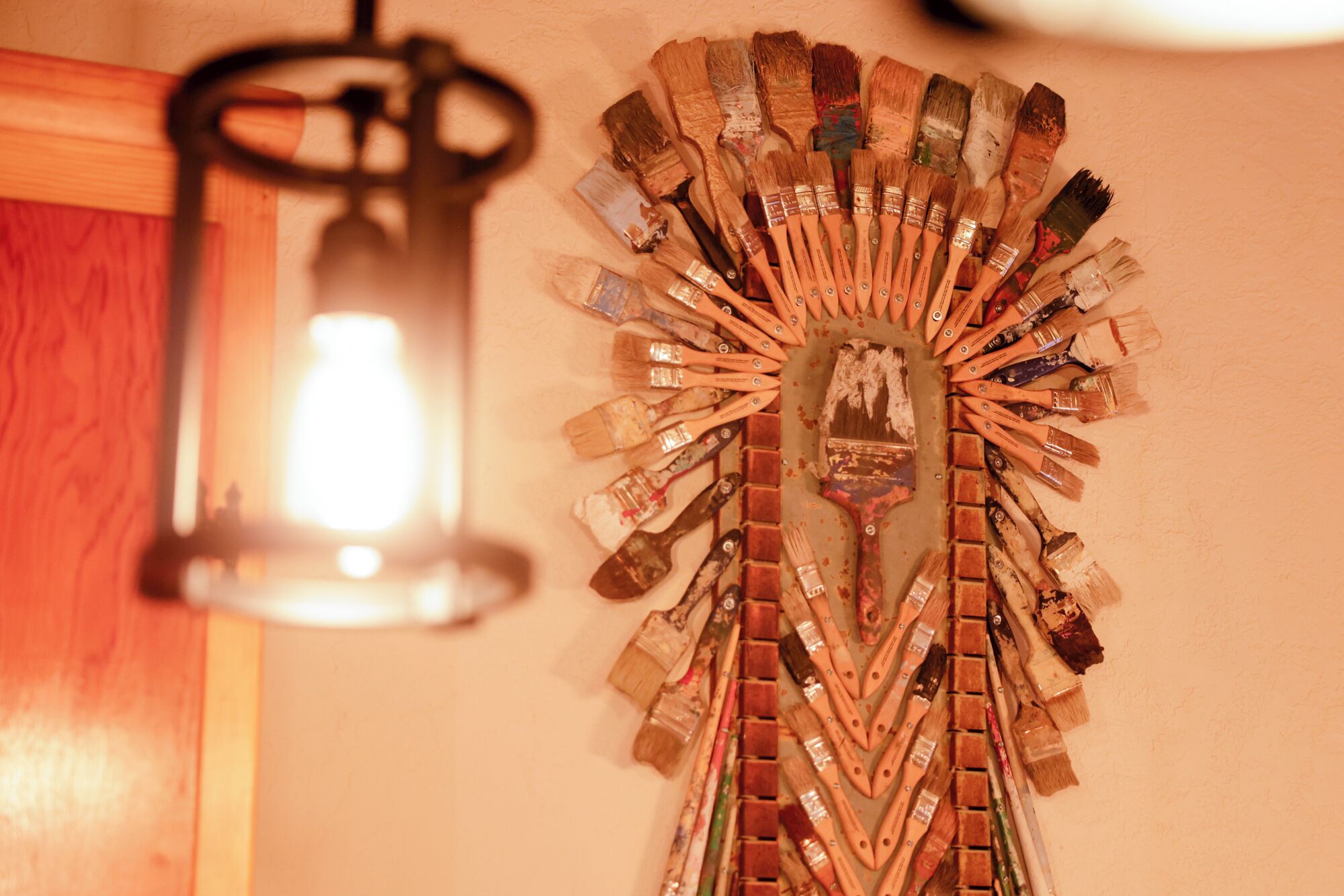 Una pared con una decoración de pinceles y un farol colgante.