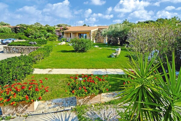A house with a garden, a lawn, and a pathway. - Apartment in Palau Near Surfing Paradise (Palau)
