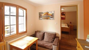 Een knus ingerichte kamer met een houten tafel, een bruine bank, een radiator en een schilderij van een auto aan de muur.