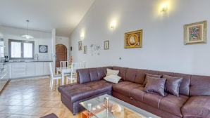 A modern living room with a brown leather sofa, a glass coffee table, and a dining area with a white table and chairs. - Pool House Kristina Near Pore (Kastelir-Labinci)
