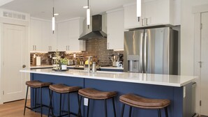 A modern kitchen with a central island, stainless steel appliances, and bar stools.