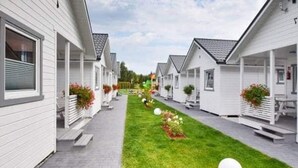 A row of white mobile homes with attached porches, a paved walkway, and a well-maintained lawn. - Comfortable Holiday Homes With Terraces (Mielno)