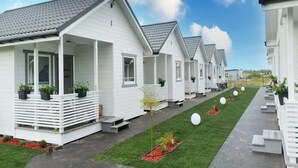 A row of white cabins with grey roofs, each with a porch and potted plants. - Comfortable Holiday Homes With Terraces (Mielno)